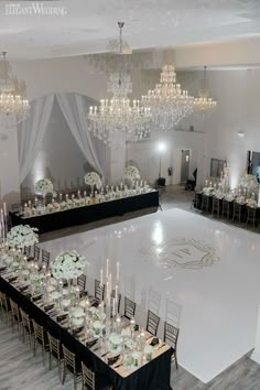 an empty ballroom with chandeliers and tables set up for a wedding reception at the end of the dance floor