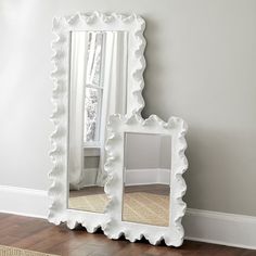 a white mirror sitting on top of a hard wood floor next to a window and rug