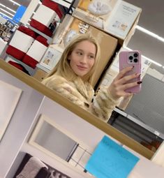 a woman taking a selfie with her cell phone in front of a store display