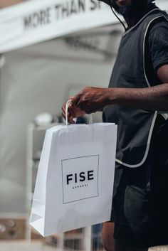 a man holding a white shopping bag with the word fise on it in front of him