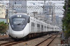 a white train traveling down tracks next to tall buildings and power lines in the background