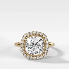 a yellow gold engagement ring with a cushion cut diamond surrounded by round brilliant pave diamonds