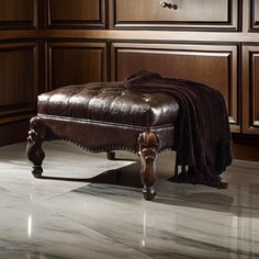 a brown leather ottoman sitting on top of a white marble floor next to wooden cabinets