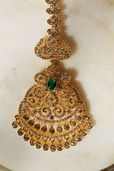 Enhance your traditional allure with the 'Jirisa - Gold AD Maang Tikka.' This exquisite piece, measuring approximately 5.51 inches in height and 1.77 inches in width, is available in two stunning options: Gold and Green, and Gold and Ruby-Green, each adding a touch of elegance to complement your style. The Gold and Green variant delicately features small teardrop-shaped stones dangling from the base, offering a subtle yet captivating charm to your appearance. Alternatively, the Gold and Ruby-Gre Ear Chain, Accessories Ear, Chandbali Earrings, Maang Tikka, Choker Necklace Set, Gold And Green, Traditional Look, Jhumka Earrings, Artisan Craft