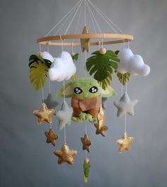 a baby yoda mobile with stars hanging from it's sides and palm trees in the background