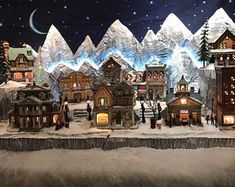 a christmas village with snow covered mountains in the background