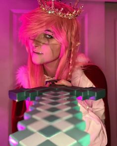 a woman with pink hair wearing a tiara and holding a checkerboard board