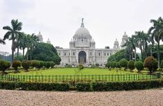 a large white building surrounded by lots of trees and bushes in the middle of a park