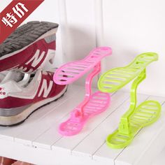 two pairs of running shoes and one pair of shoelaces sitting on top of a shelf