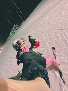 two people on skis laying down in the snow