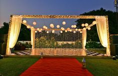 an outdoor wedding setup with white lanterns and red carpet