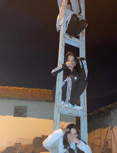 two girls standing on a ladder with their arms around each other