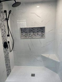 a walk in shower sitting next to a white tiled wall and floor with black accents