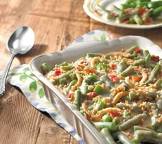 a casserole dish filled with green beans, peas and carrots on a wooden table