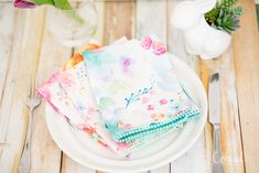 three napkins on a plate with flowers in the background