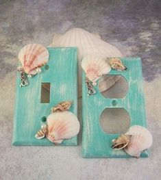 two seashells are sitting on a light switchplate in front of a sea shell