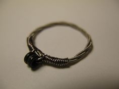 a close up of a metal ring on a white surface with a black bead around it