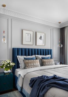 a large bed with blue headboard and pillows in a bedroom next to a window