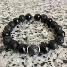 Lava Stone, Matte Black Onyx, And Onyx 10mm Bracelet w/ Silver Accents Mixed, matched, and designed with a variety of elegant beads for a graceful look. This is a beautiful piece made to be worn separately or combined with our other Embody'd Art pieces! This bracelet can also be worn as an oil diffuser. Just add one drop of your favorite oil to the AAA grade lava beads and you're set to go. This bracelet is crafted with quality elastic stretch cord. This bracelet is also designed to fit snug on Adjustable Black Beaded Bracelets With Polished Beads, Adjustable Black Wristband With Gemstone Beads, Black Gemstone Beads Rosary Bracelet Gift, Black Rosary Bracelet With Gemstone Beads As Gift, Black Beaded Bracelets For Healing With 8mm Beads, Black Beaded Bracelets With 8mm Beads For Healing, Black Healing Beaded Bracelets With Round Beads, Black Stretch Bracelet With Polished Beads, Adjustable Black Gemstone Beaded Bracelets