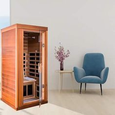 a room with a blue chair and a wooden sauna in the corner next to a window