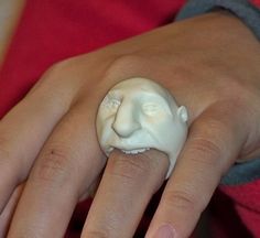 a woman's hand with a ring made to look like a face on it