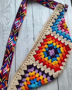 a colorful crocheted purse with a multicolored neck tie hanging from it