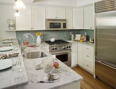 a kitchen with marble counter tops and stainless steel appliances, along with white cabinetry