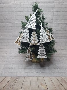 a christmas tree made out of cutout paper on top of a wooden table next to a brick wall