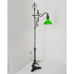 a floor lamp with a green shade on it's side in a white room