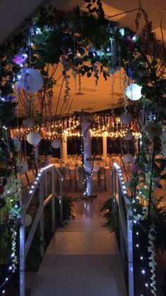 an archway decorated with lights and greenery at the end of a long hallway leading to a dining room