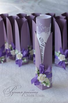 purple wedding favors with white flowers and ribbons on the top are lined up in rows