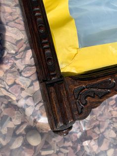 a wooden frame sitting on top of a pile of rocks next to a yellow and blue flag