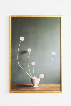 a vase with white flowers in it sitting on a table next to a framed photograph