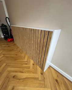 an empty room with hard wood flooring next to a wall and a vacuum cleaner