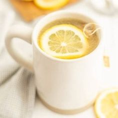 a white cup filled with liquid and sliced lemons