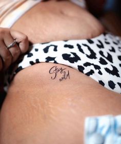 a woman with a tattoo on her thigh that says stay wild in cursive writing