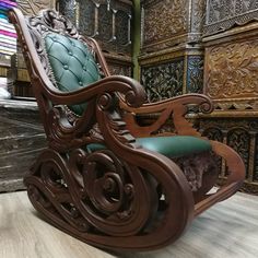 an ornate wooden rocking chair with blue leather seat and armrests, in front of intricately carved wood paneled walls