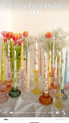 there are many candles on the table with flowers in them