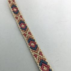 a beaded bracelet on a white surface with a red, blue and yellow design