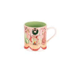 a coffee cup with a christmas scene on the front and green trimmings around it