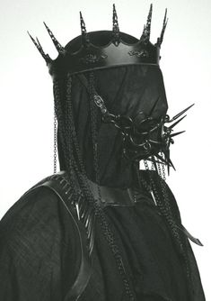 a man with metal spikes on his head wearing a black outfit and chainmails