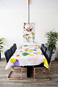 a dining room with a table, chairs and potted plants on the wall behind it