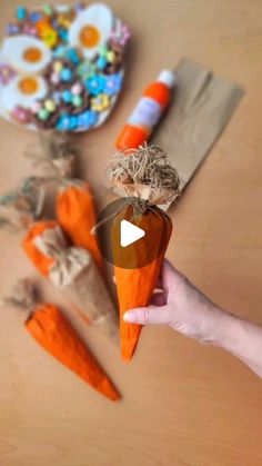 a person holding an orange carrot in front of some other carrots on a table