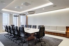 an empty conference room with black chairs and a white table in front of large windows