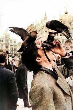 a man is holding a bird on his head