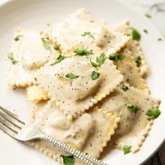 a white plate topped with ravioli covered in gravy