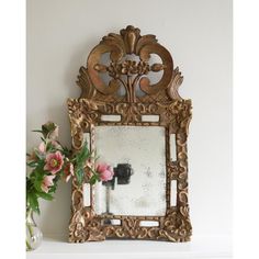 a mirror sitting on top of a shelf next to a vase with flowers