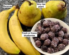 a bowl filled with fruit next to two pears and some chocolate covered bites in front of them