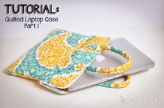 an ipad case made out of fabric with yellow and blue flowers on the front, sitting on top of a white surface