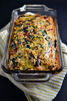 a casserole dish with mushrooms and spinach in it on a yellow towel